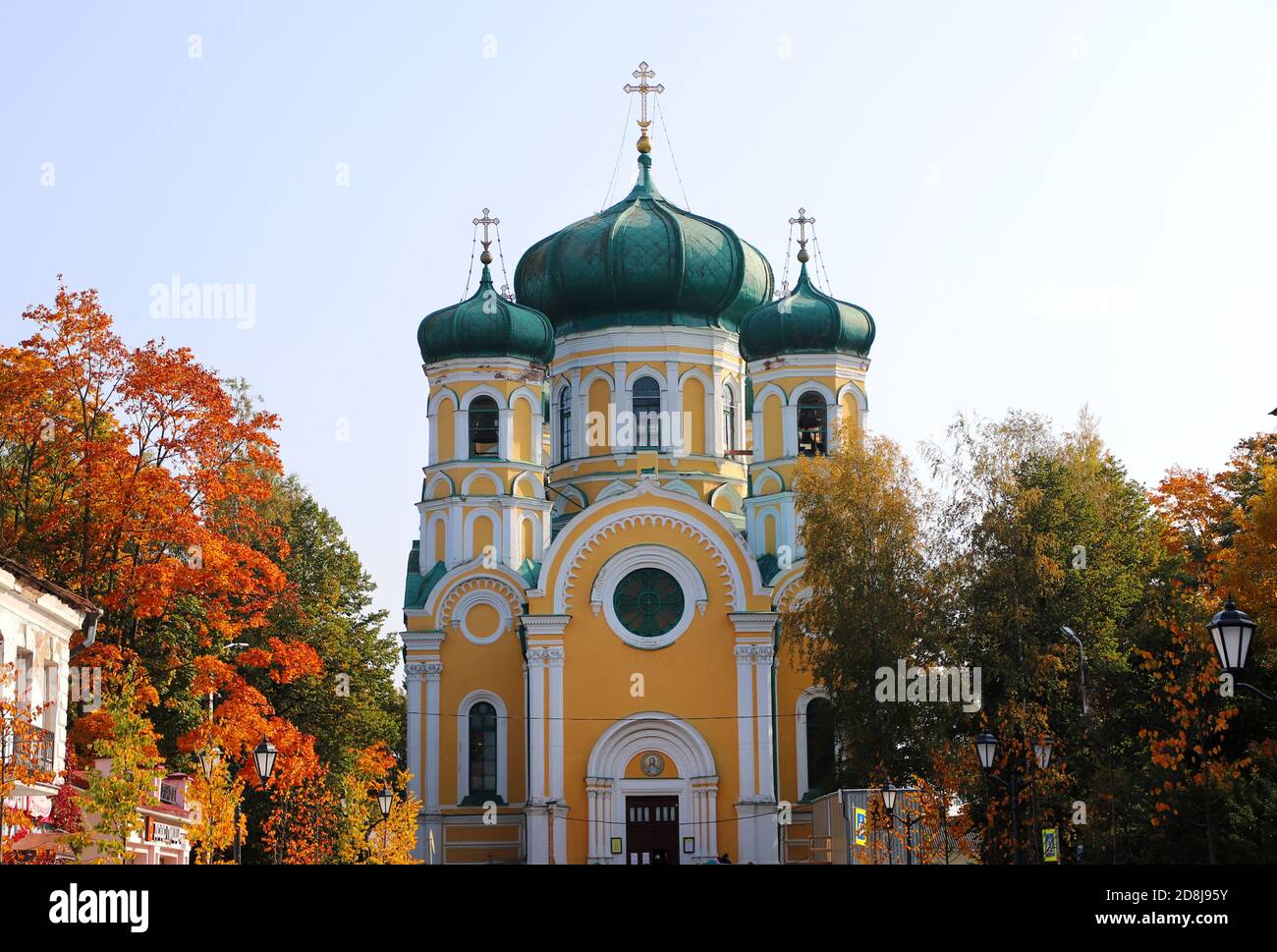 Weiße und gelbe orthodoxe Kirche mit dunkelgrünen Kuppeln umgeben Durch bunte Herbstblätter Stockfoto