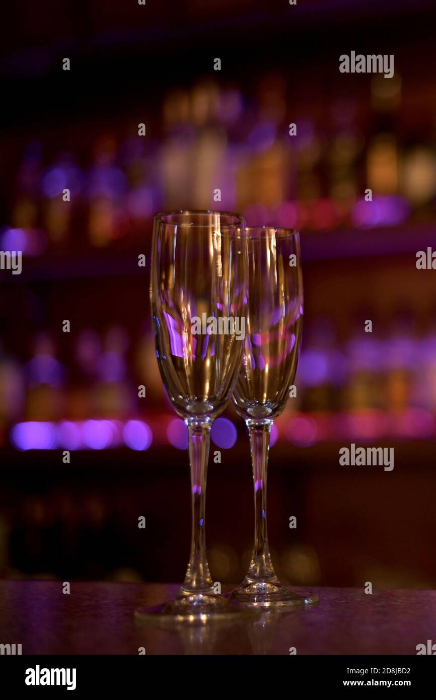 Zwei Weingläser gefüllt mit violett gefüllten Hintergrundlichtern und Glasglanz. Stockfoto