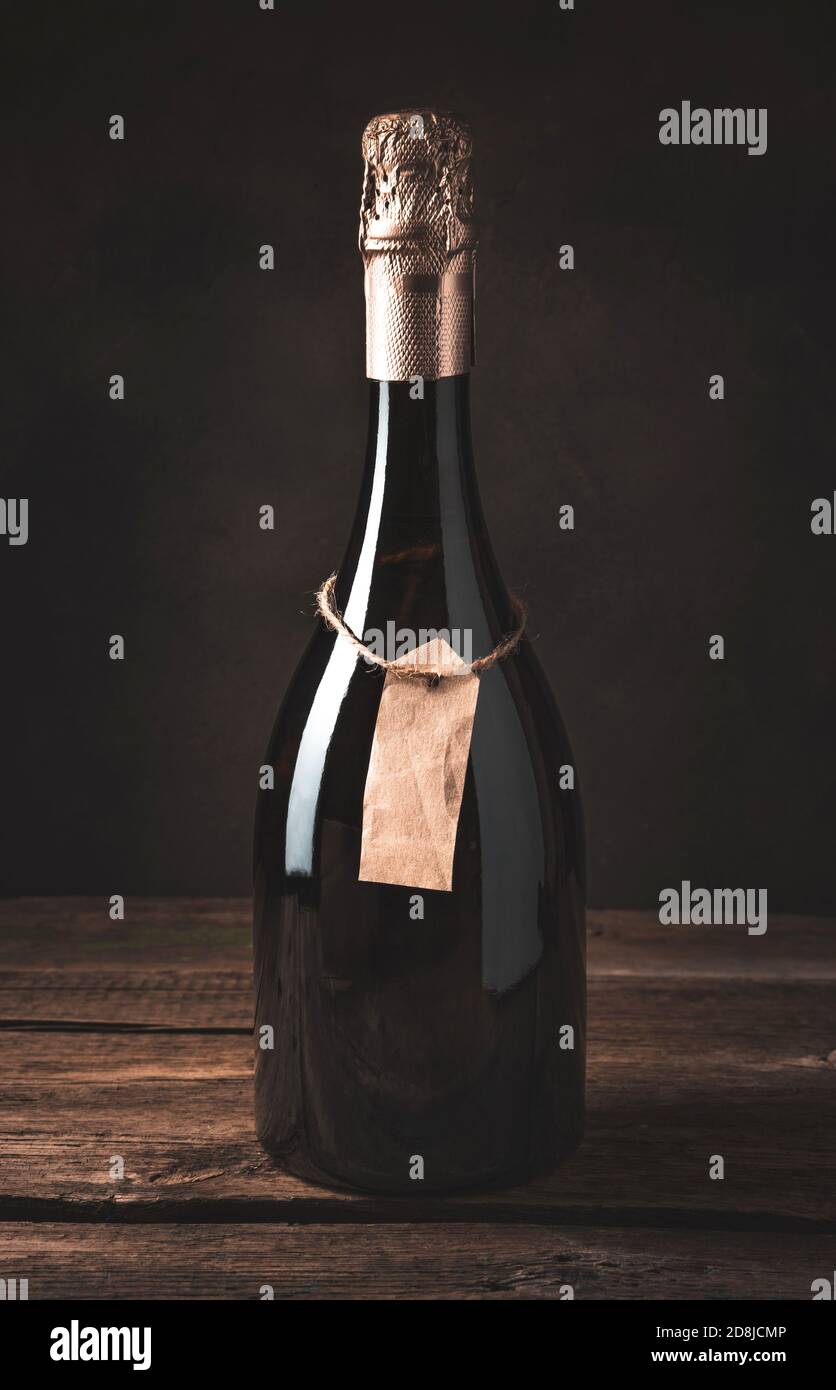 Sekt in einer geschlossenen Flasche mit einem Handlabel auf einem Holzhintergrund. Stockfoto