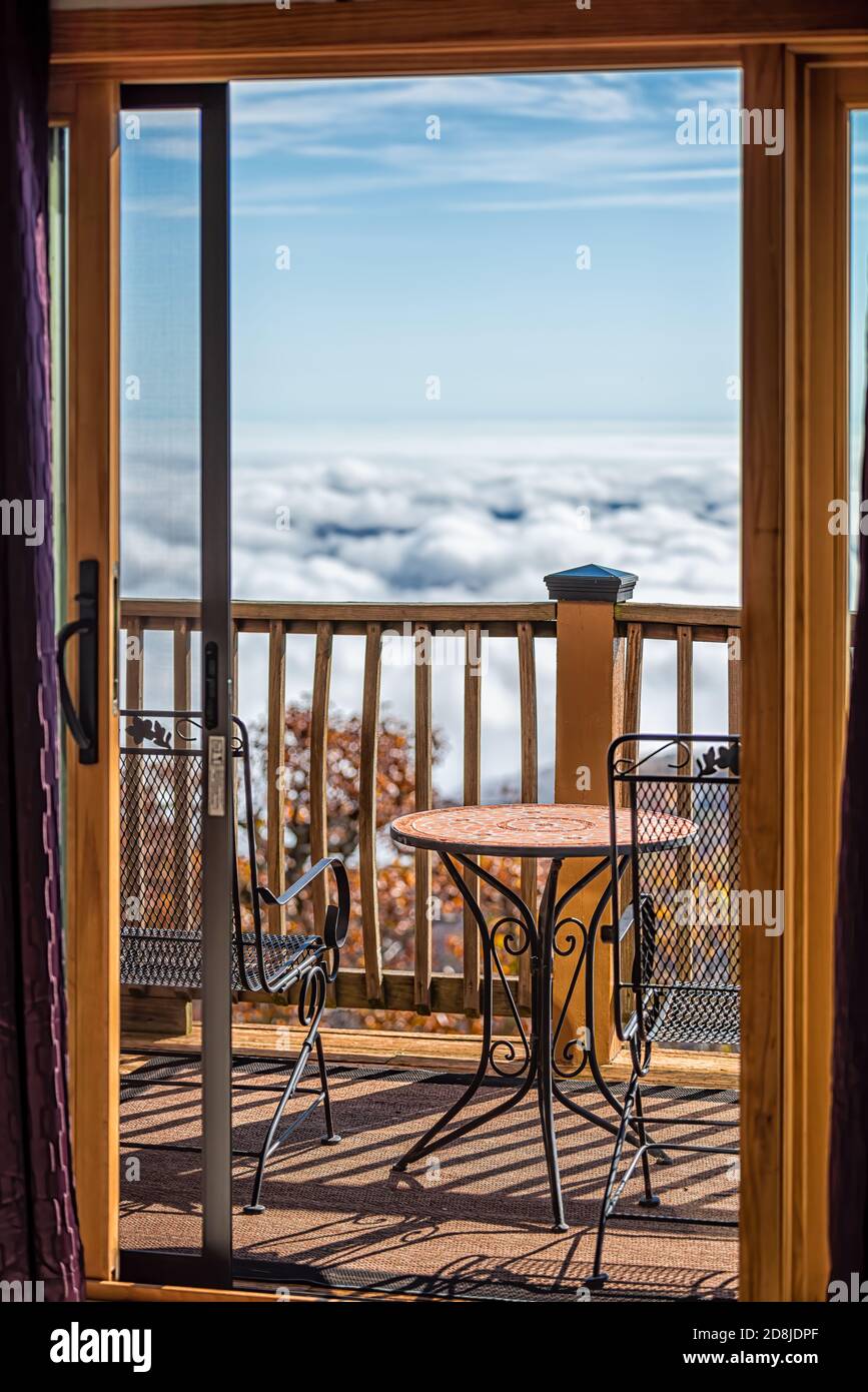 Balkonterrasse draußen in Wintergreen, Virginia mit blauem Bergblick und Wolkeninversion mit blauem Himmel und Sonnenlicht auf Stühlen Tischgeländer Stockfoto