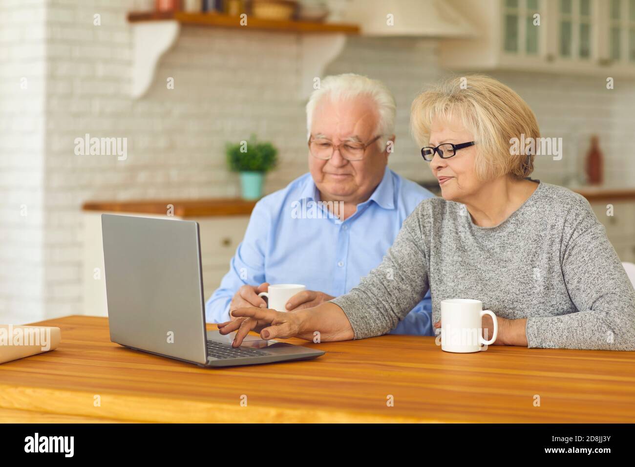 Glückliches Seniorenpaar, das zu Hause vor dem Laptop sitzt Und Videoanrufe bei Enkelkindern Stockfoto