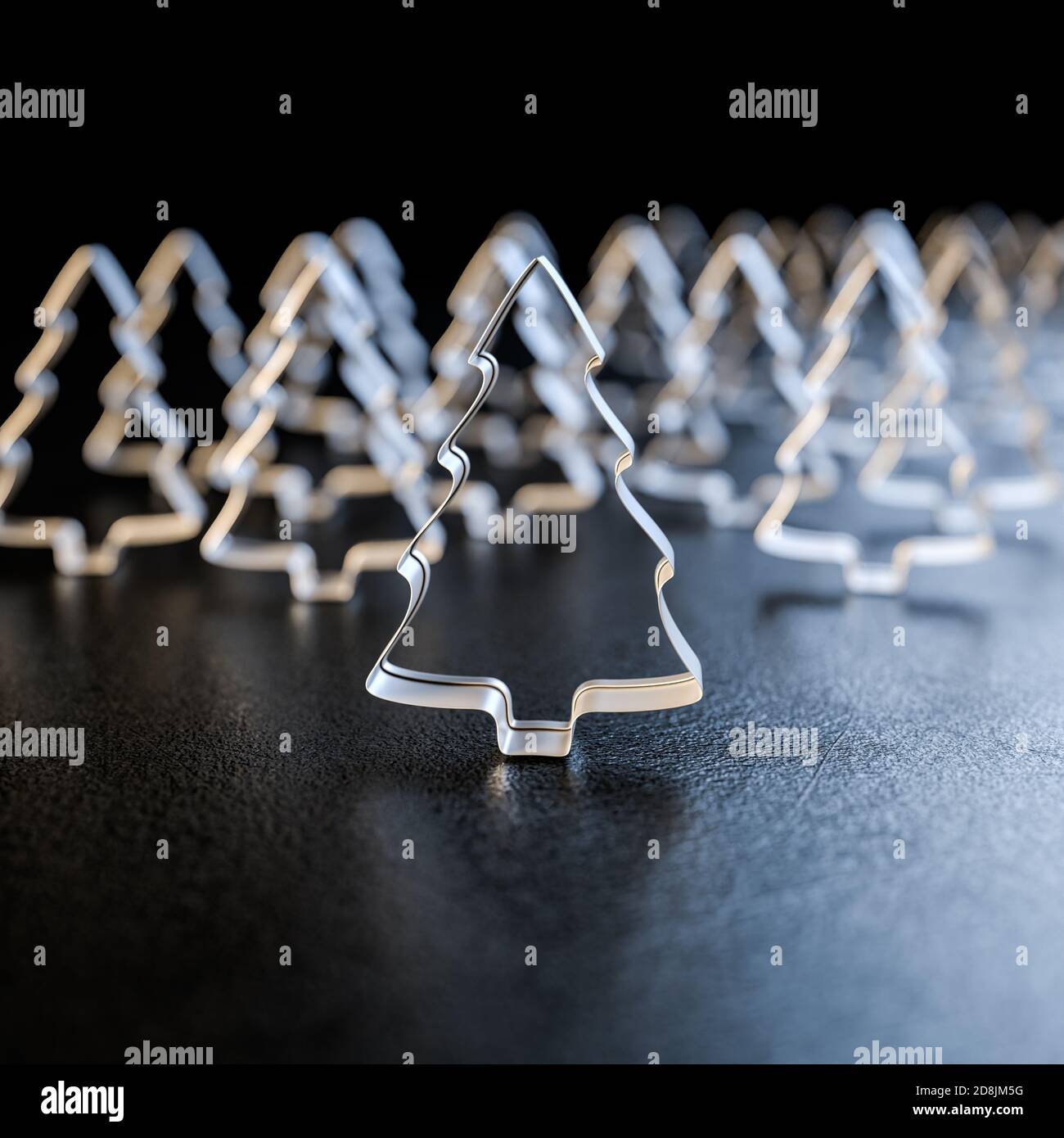 Ein Wald von Weihnachtsbaum-Keksausstecher, die auf einer Arbeitsplatte stehen. Quadratische Zusammensetzung für bessere Zuschneidemöglichkeiten. Selektiver Fokus Stockfoto