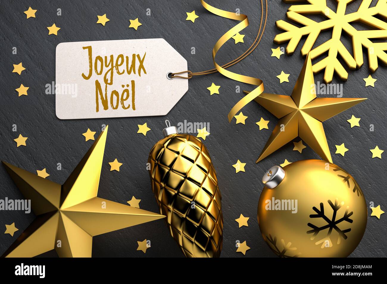 Weihnachten - Geschenk-Tag mit der französischen Frohen Weihnachtsbotschaft 'Joyeux Noël' auf schwarzem Steingrund mit goldfarbenen weihnachtsornamenten. Stockfoto