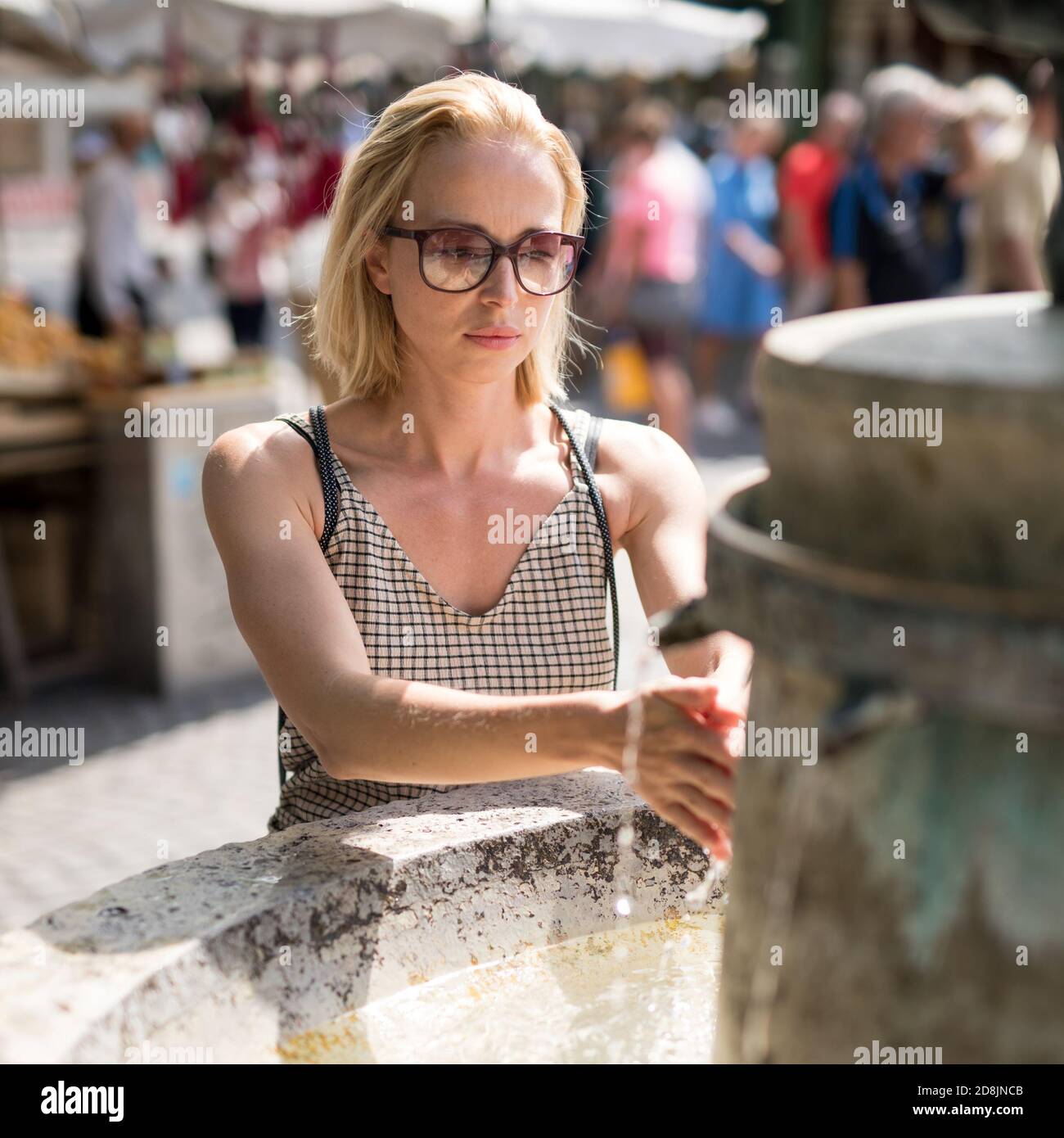 Junge Casual cucasian Frau waschen Hände mit Wasser aus der Öffentlichkeit Stadtbrunnen an einem heißen Sommertag Stockfoto