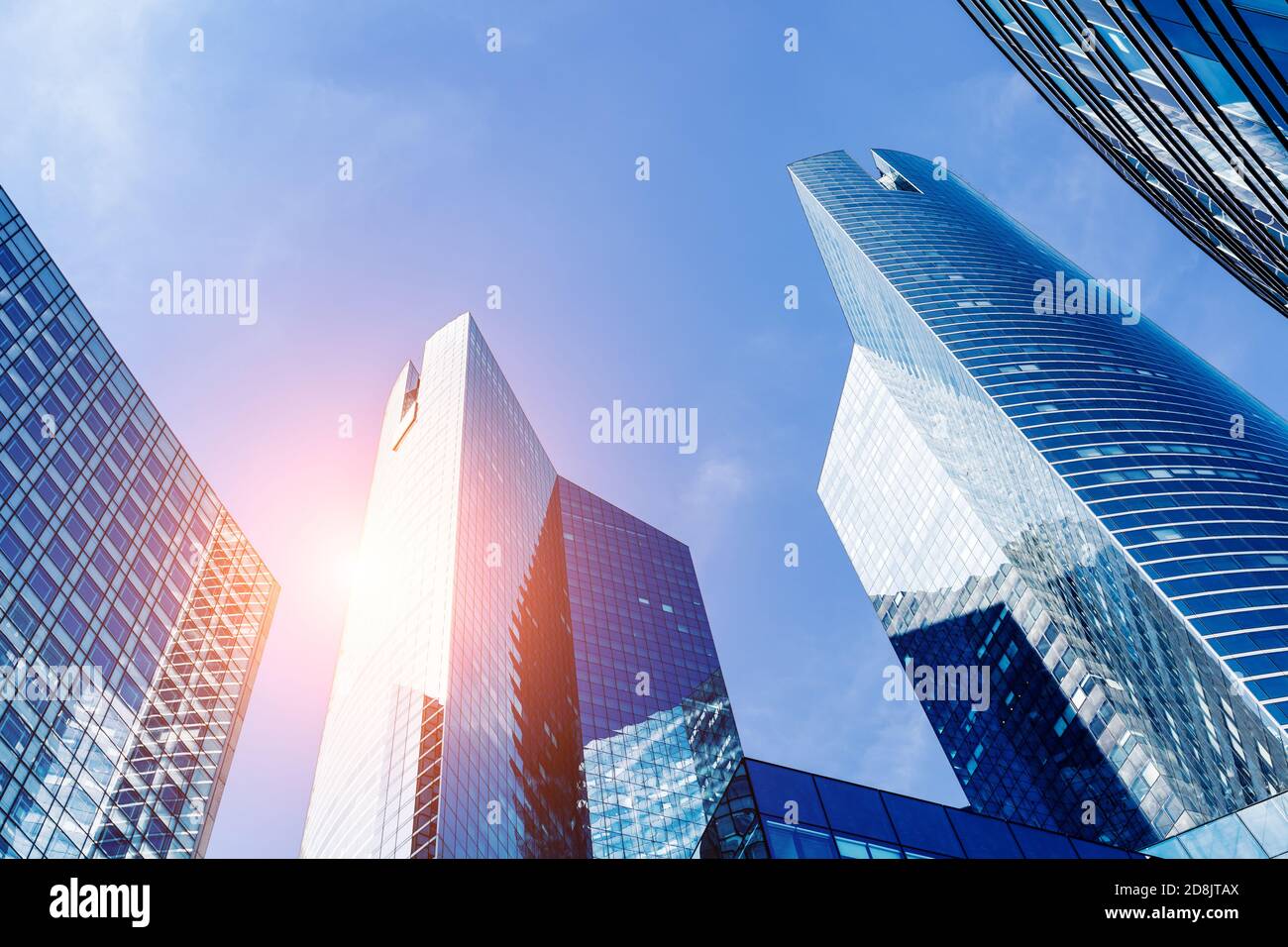Bürogebäude im Finanzviertel mit Sonnenlicht und Himmel, die sich in den modernen Glaswänden von Wolkenkratzern spiegeln. Geschäftshintergrund. Niedriger V-Winkel Stockfoto
