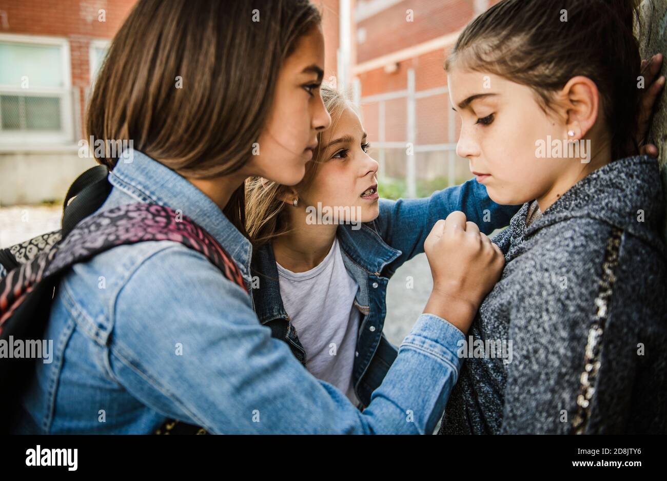 Ein trauriges Mädchen Einschüchterung Moment auf der elementaren Alter Mobbing Auf dem Schulhof Stockfoto