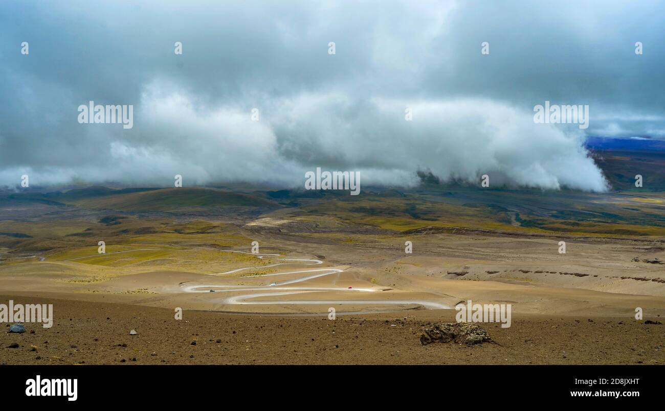 Kurvenreiche Straße durch das Tal des Vulkans Cotopaxi und niedrige Wolken in der Ferne, Cotopaxi, Ecuador Stockfoto