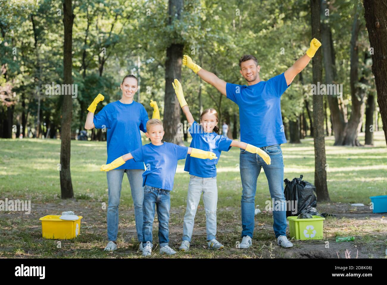 Eltern zeigen Erfolg Geste, und Kinder gestikulieren mit Händen in der Nähe von Behältern mit Müll, Ökologie Konzept Stockfoto