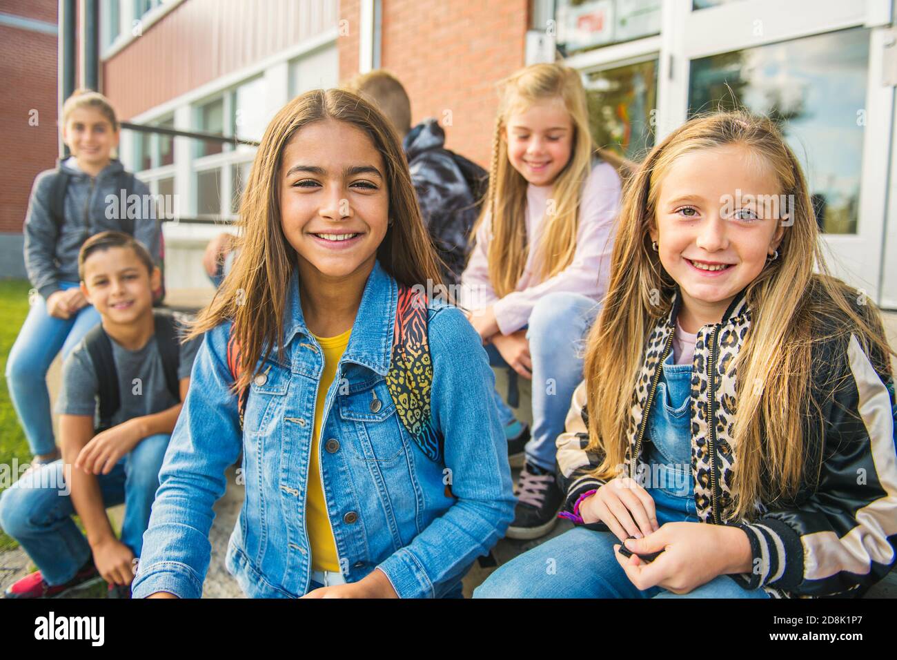 Eine Gruppe von Kindern sitzt auf der Schultreppe und hat Spaß Stockfoto