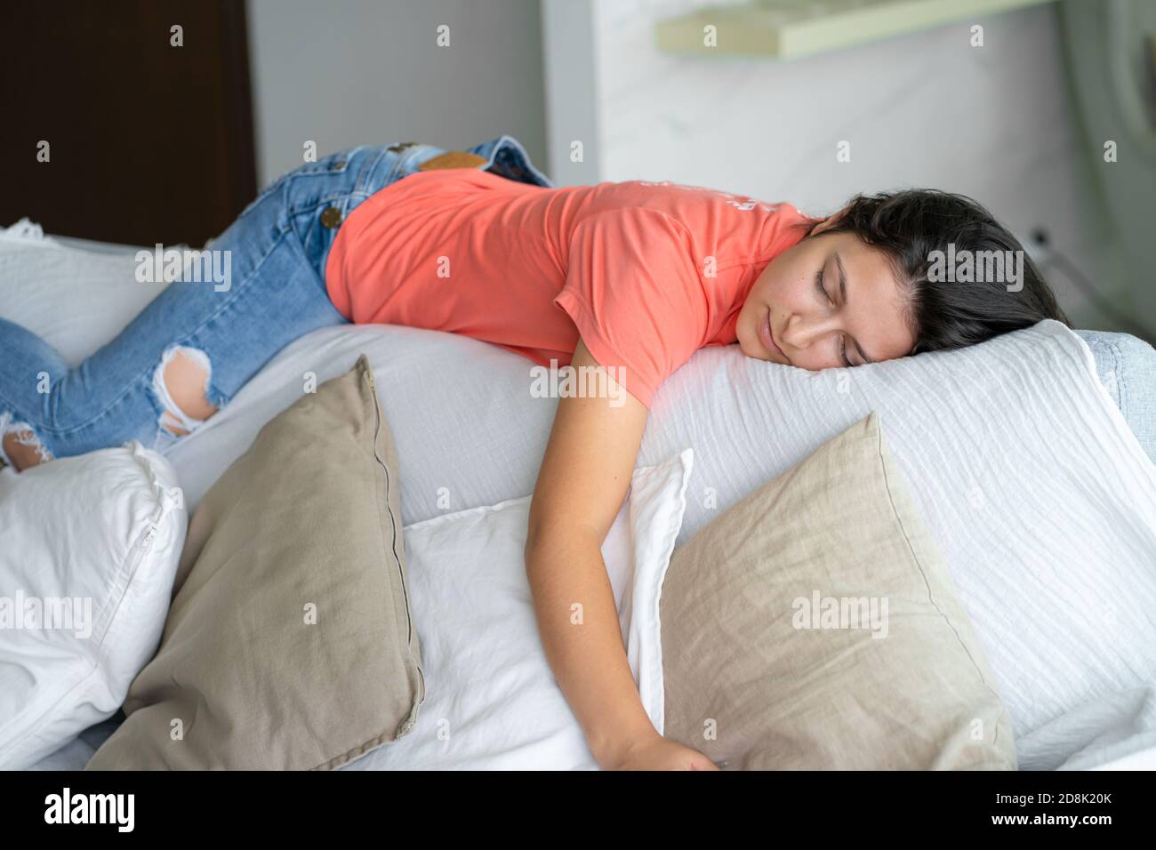 Das Mädchen schlief in einer ungewöhnlichen Position auf der Rückseite des Sofas ein. Schlaf tagsüber. Energierückgewinnung. Stockfoto