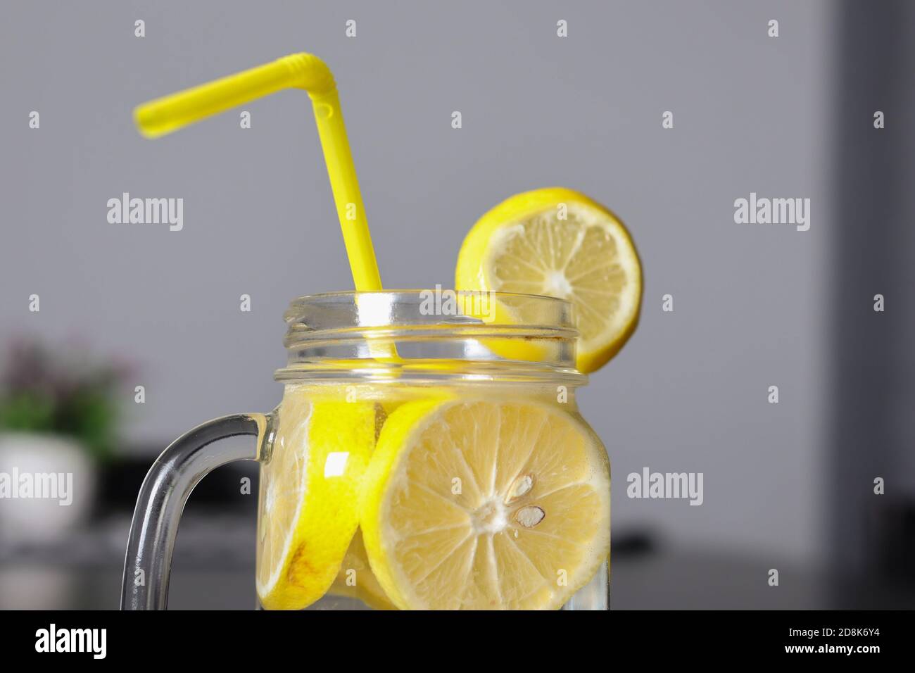 Nahaufnahme der Limonade in einem Glas mit Zitronenscheiben und einem Trinkschlauch. Konzept für gesunde Getränke Stockfoto