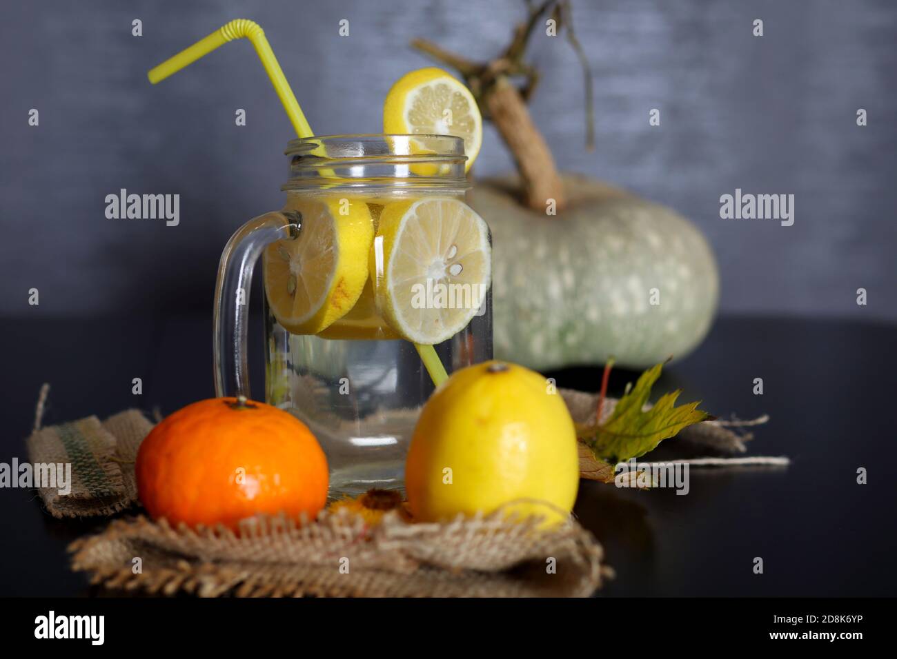 Limonade in einem Glas mit Zitronenscheiben und einem Trinkschlauch auf einem dekorierten Holzschreibtisch. Konzept für gesunde Getränke. Nahaufnahme, selektiver Fokus Stockfoto