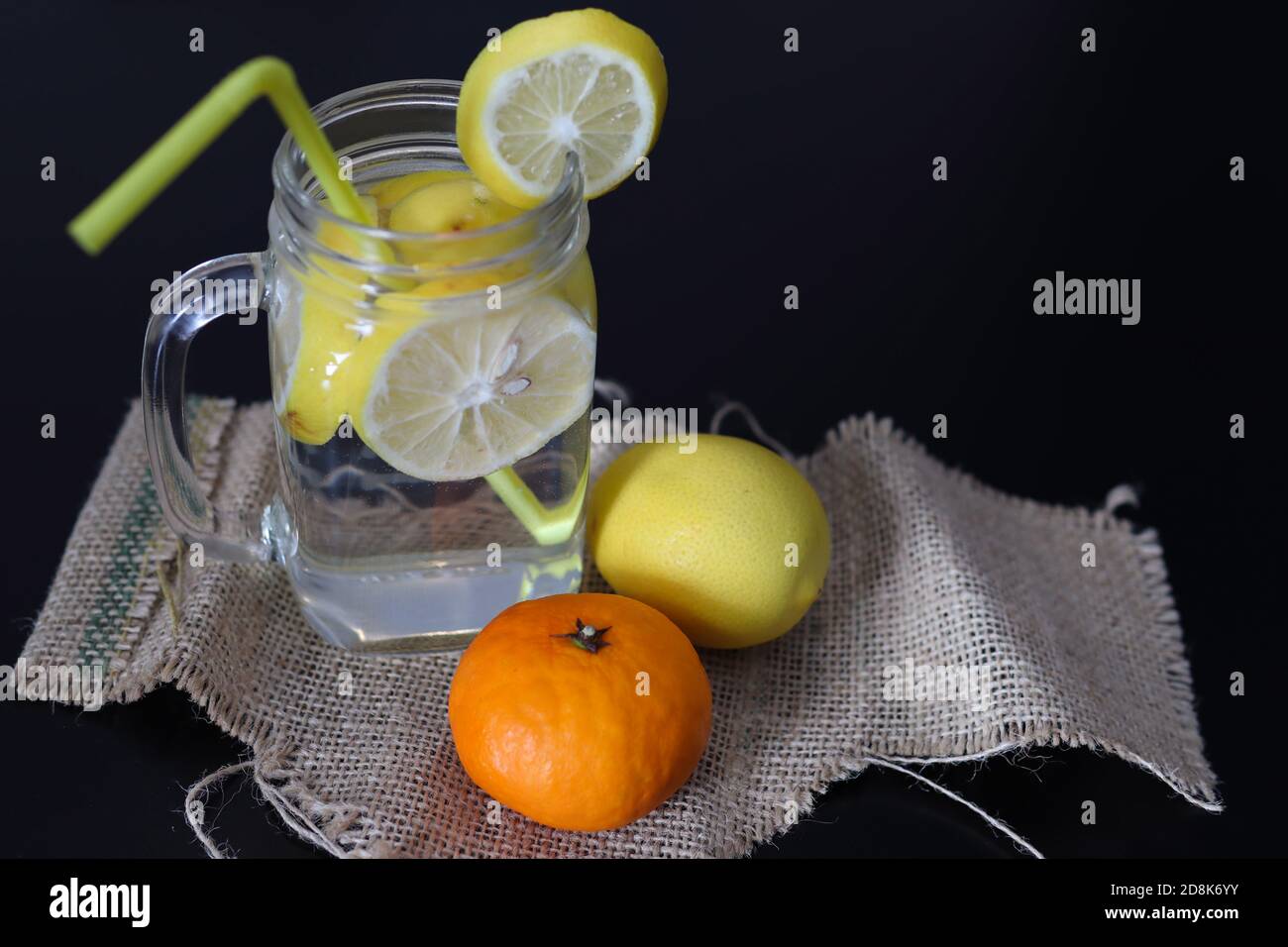 Limonade in einem Glas mit Zitronenscheiben und einem Trinkschlauch auf einem dekorierten Holzschreibtisch. Konzept für gesunde Getränke Stockfoto