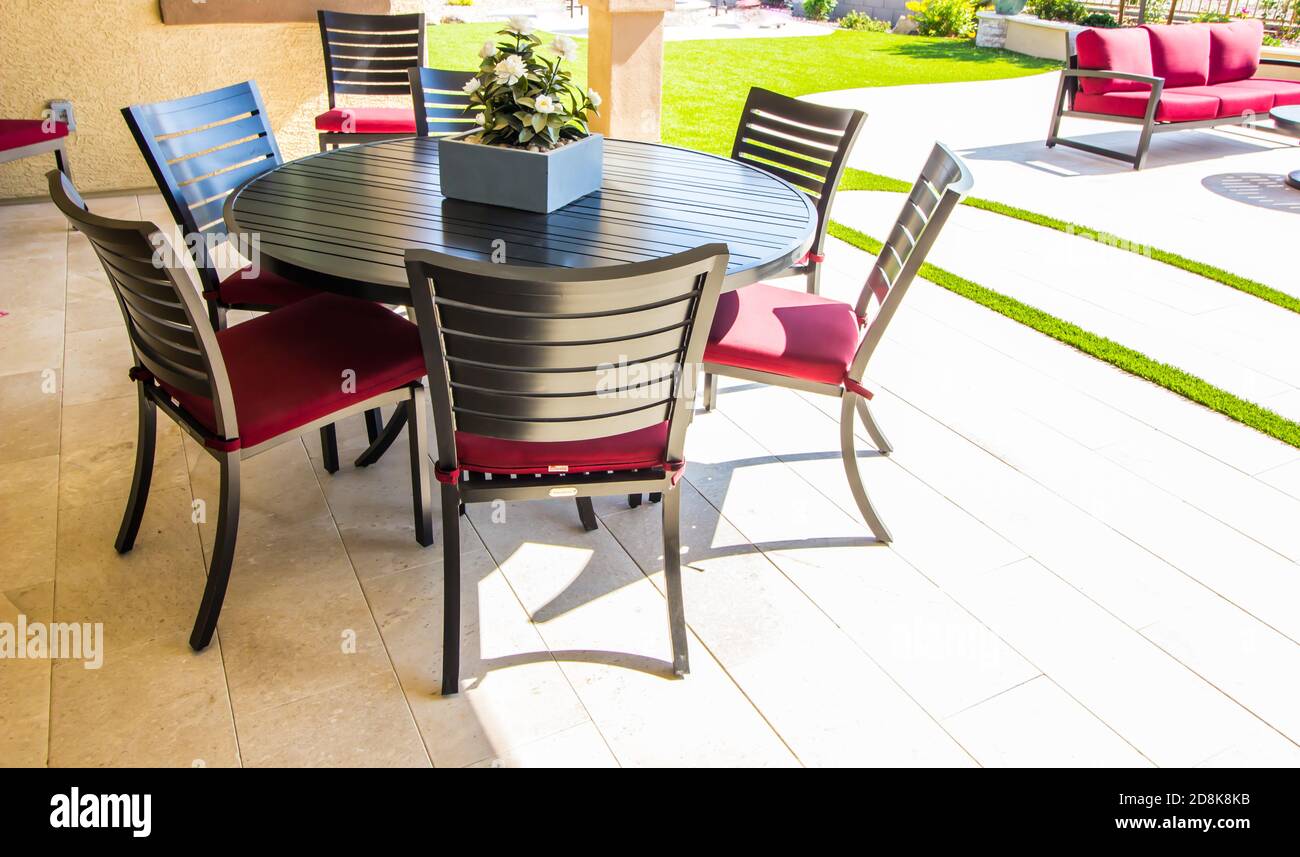 Hinterer Patio Runder Metalltisch Mit Sechs Stühlen Und Rot Sitzkissen Stockfoto
