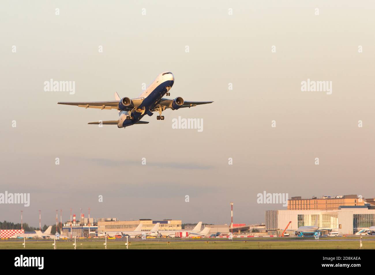 Flugzeug, das am Sommertag abfliegt, Flughafen im Hintergrund. Flugzeug fliegt bei Sonnenuntergang hoch. Urlaub, Flugkonzept Stockfoto
