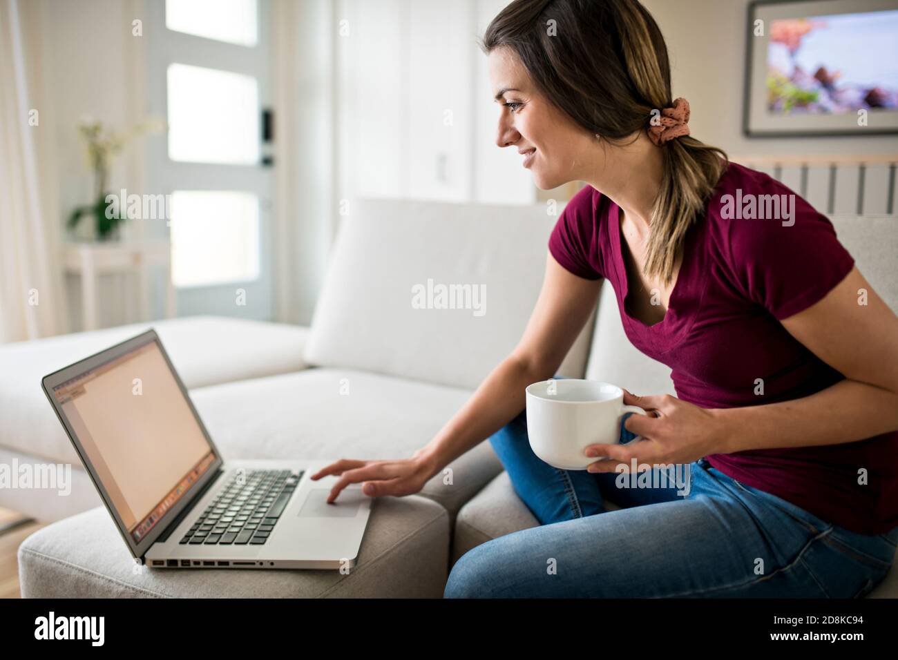 Brunette mit gute Zeit auf dem Wohnzimmer mit Kaffee Und Laptop Stockfoto