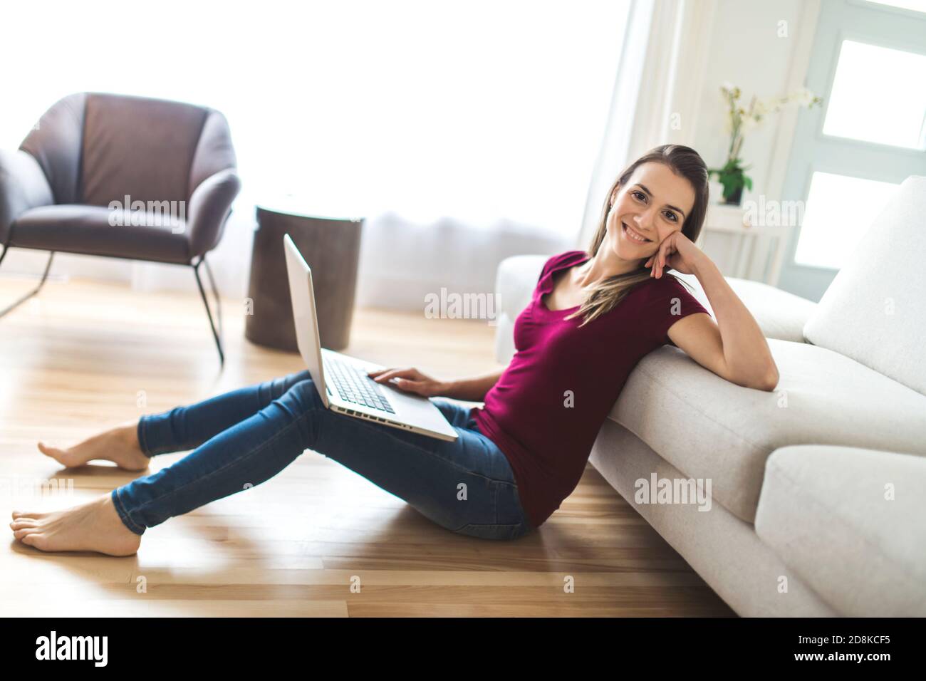 Brunette mit gute Zeit auf dem Wohnzimmer mit Laptop Stockfoto