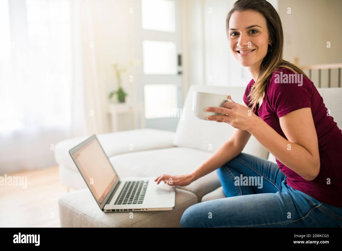Brunette mit gute Zeit auf dem Wohnzimmer mit Kaffee Und Laptop Stockfoto
