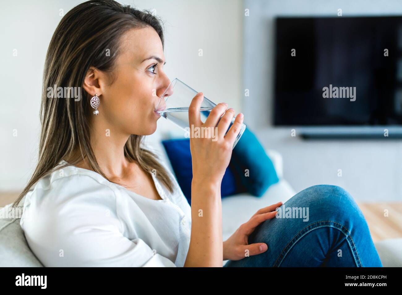 Brunette mit gute Zeit auf dem Wohnzimmer mit Wasser Glas Stockfoto