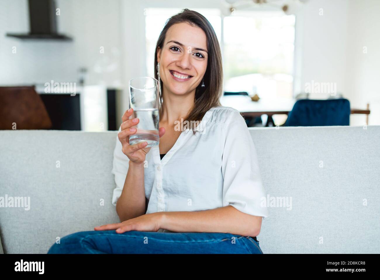 Brunette mit gute Zeit auf dem Wohnzimmer mit Wasser Glas Stockfoto