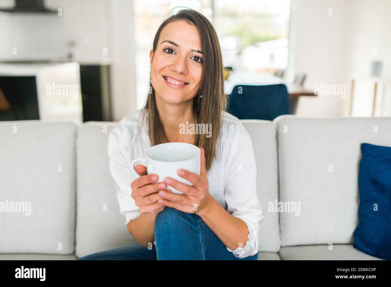 Brunette trinkt eine Tasse Kaffee im Wohnzimmer Stockfoto