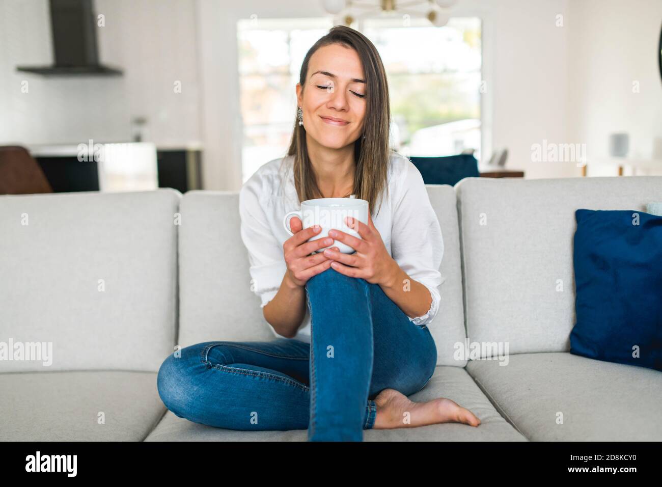 Brunette trinkt eine Tasse Kaffee im Wohnzimmer Stockfoto