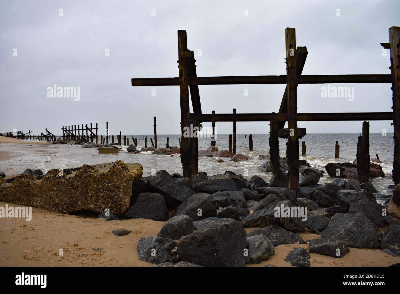 Die alten hölzernen Meeresverteidigungen entlang Happisburgh Beach in Norfolk, Großbritannien. Hier platziert, um eine weitere Costalerosion zu verhindern. Stockfoto