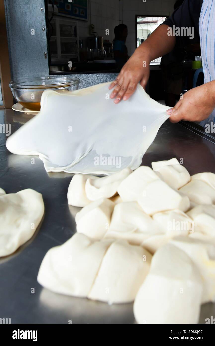 Nahaufnahme der Hände einer Frau, die Roti-Teig mit Öl auf dem Edelstahltisch knetet. Bewegungsunschärfe. Stockfoto