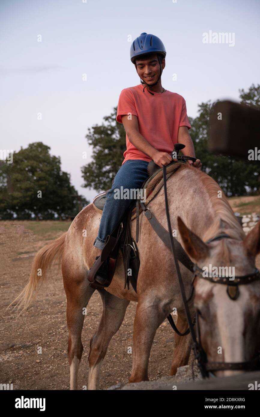 Ein Mann, der auf einem Pferd sitzt, wenn das Pferd isst. Ranch Konzept Fotografie Stockfoto