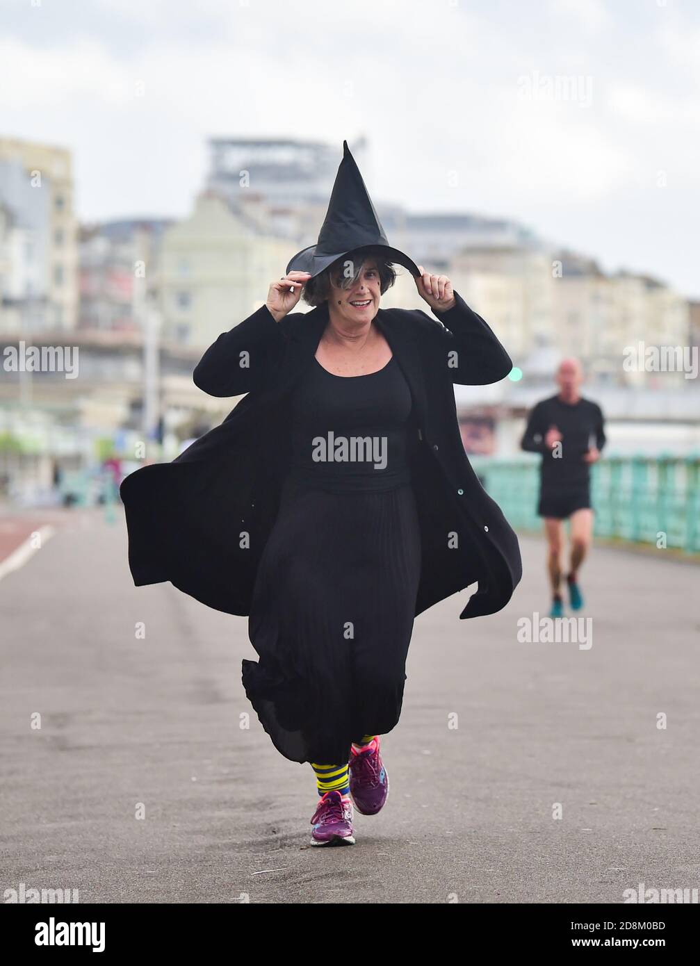 Brighton UK 31. Oktober 2020 - EINE Halloween Hexe hängt an ihrem Hut, als sie für Wohltätigkeitsorganisationen entlang Brighton Küste läuft, als Storm Aiden Teile von Großbritannien mit Warnungen vor großen Winden und möglichen Schäden an Eigentum beeinflusst : Credit Simon Dack / Alamy Live News Stockfoto