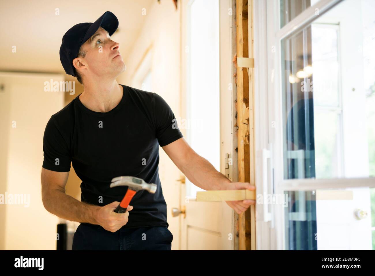 Ein hübscher junger Mann, der doppelte Schiebetür in der Terrasse installiert Eine neue Hausbaustelle Stockfoto