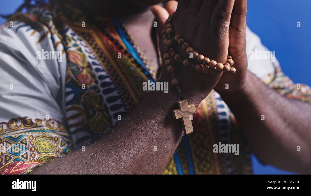 Nicht erkennbarer afrikanischer schwarzer Mann in traditioneller Kleidung  mit Rosenkranz beten mit Händen über der Brust. Hochwertige Fotos  Stockfotografie - Alamy