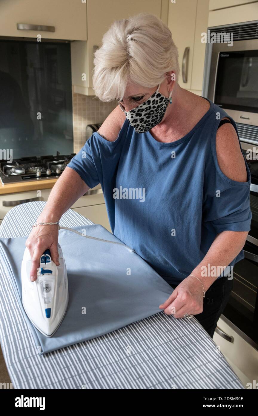 Während der aktuellen covid 19 Pandemie oder Epidemie, ein selbstständiger Haushälter oder Reiniger, trägt eine schützende Gesichtsmaske Hausarbeit Aufgaben Stockfoto