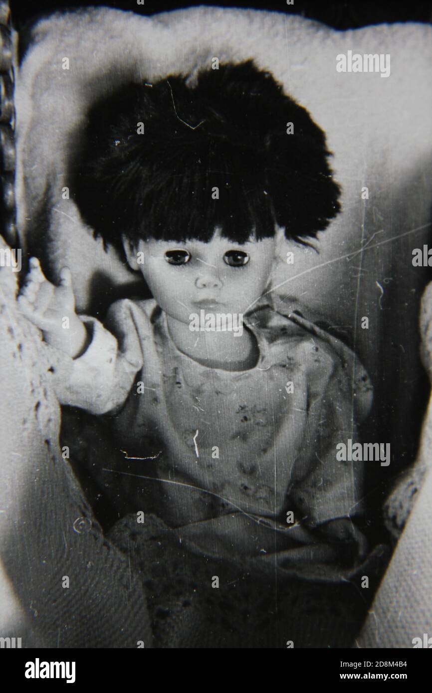 Feine Vintage-Schwarz-Weiß-Fotografie aus den 70er Jahren einer Puppe, die in einem Kinderwagen sitzt und die Kamera in einem Landhaus in den USA anschaut. Stockfoto