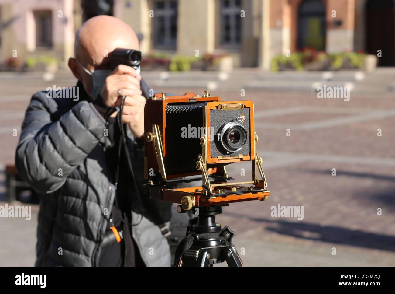 Krakau, Malopolska/Polen - 20.10.2020: Mann, der mit einer großformatigen Holzklappkamera im Vintage-Stil auf einem Stativ fotografiert. Aufnahme von Belichtungsdaten mit Stockfoto