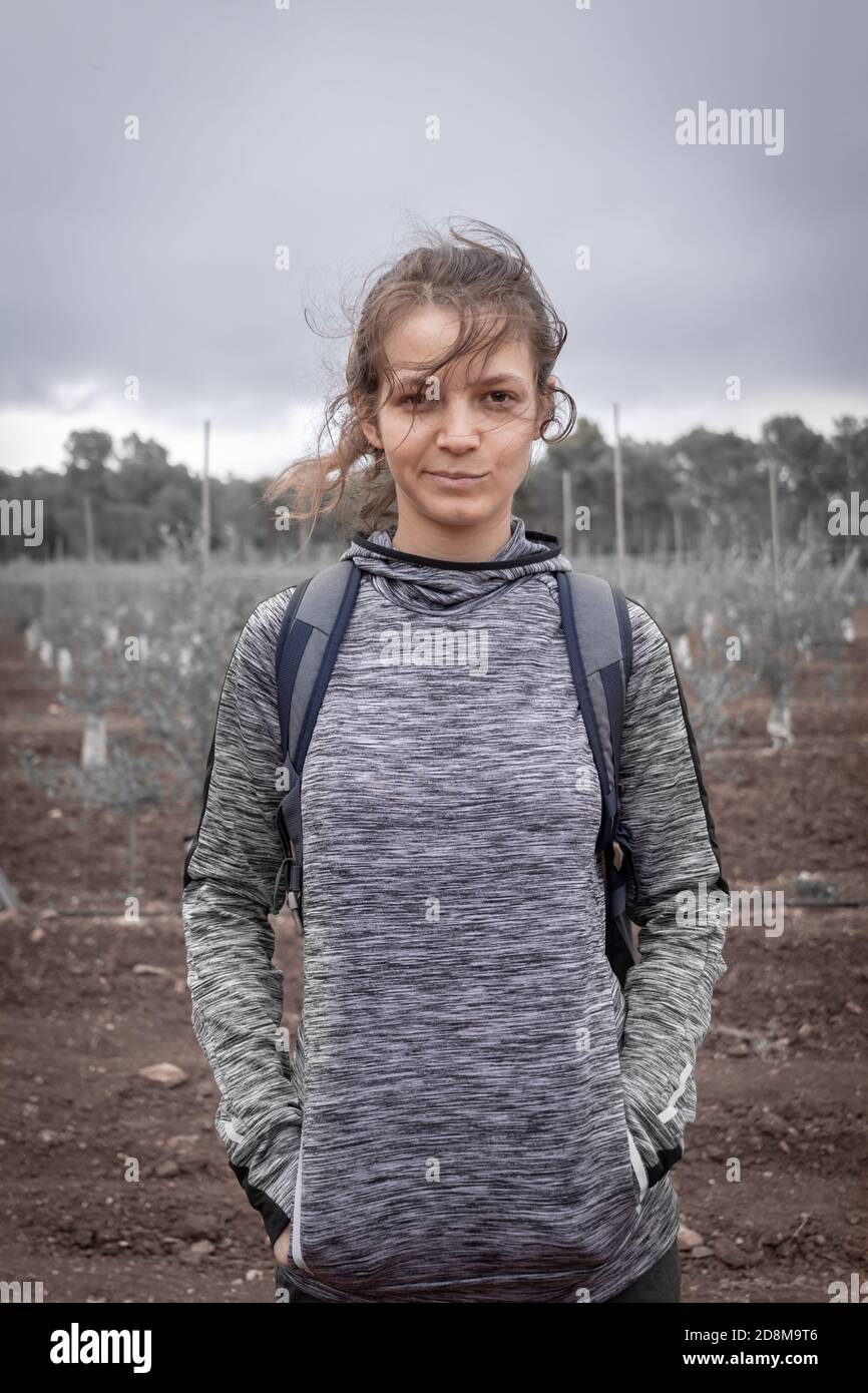 Glücklich gewagte (übermütig) junge kaukasische Frau, stehend mit den Händen in den Taschen, in sportlicher Kleidung, ländliche Umgebung. Stockfoto