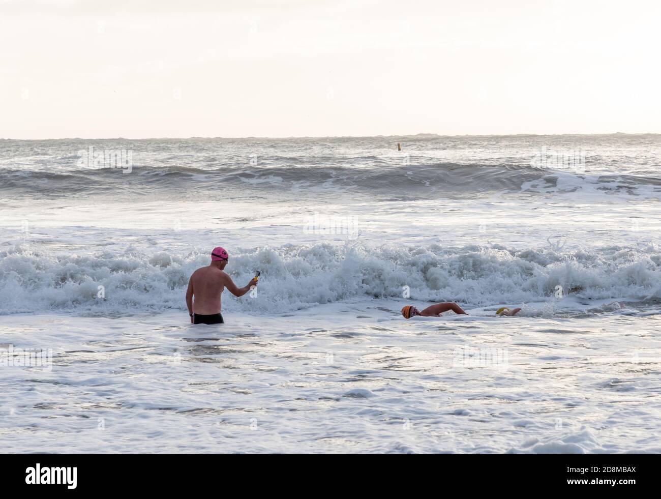 Myrtleville, Cork, Irland. Oktober 2020. Ein Mann filmt seinen Freund beim Schwimmen während des Sturms Aiden in Myrtleville, Co. Cork, Irland. - Credit; David Creedon / Alamy Live News Stockfoto