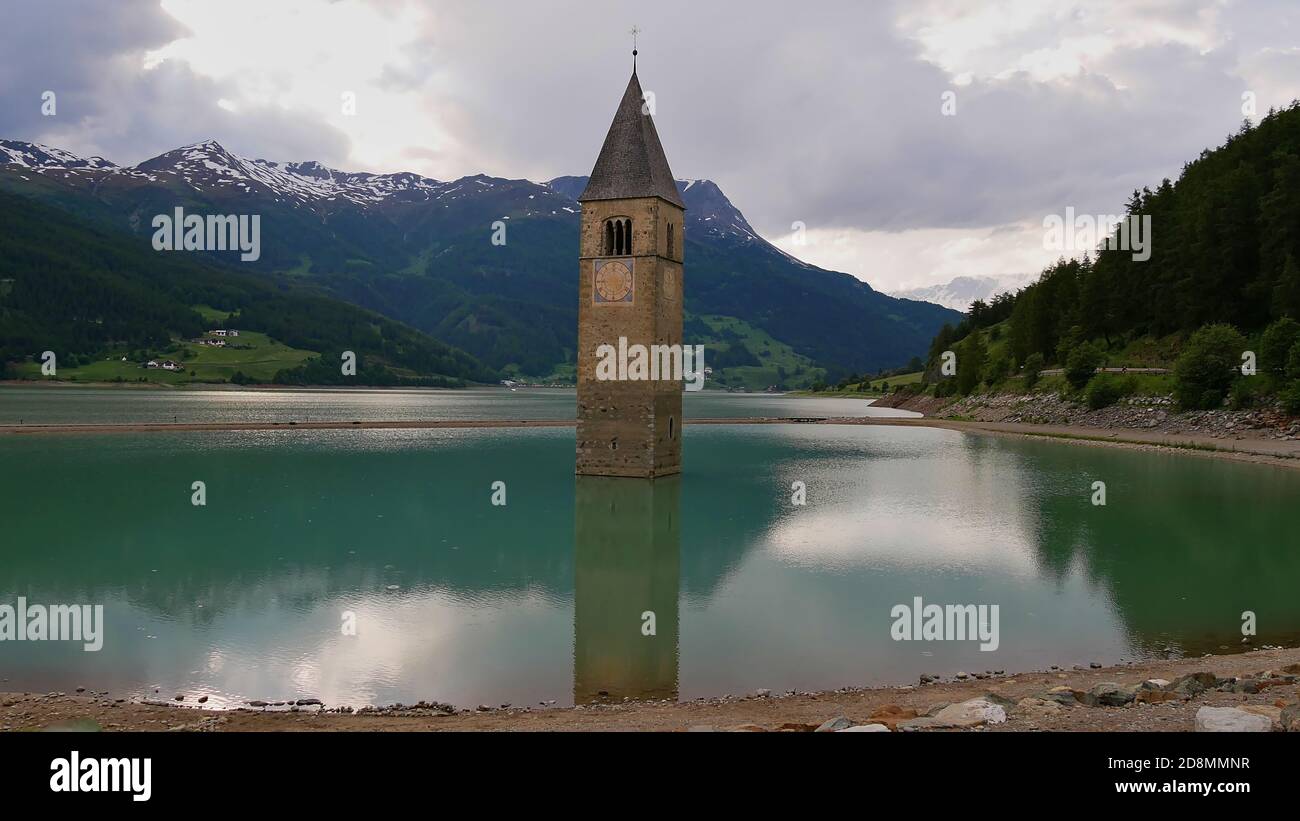 Berühmter einstehender Kirchturm im Reservoir Reschensee, Südtirol, Italien in Erinnerung an das überflutete Dorf Graun, im Frühsommer. Stockfoto