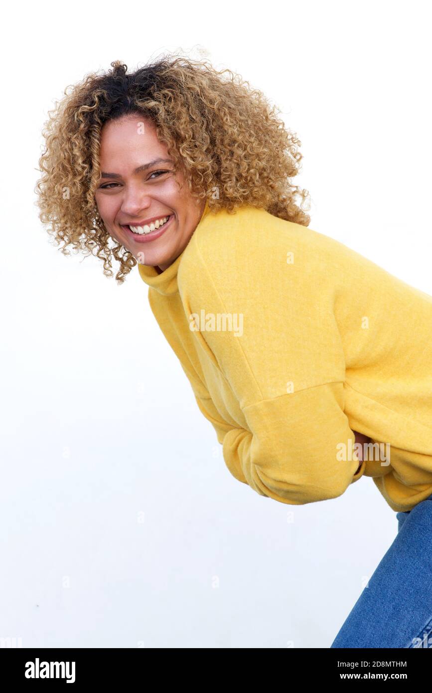 Seitenportrait der lächelnden jungen afroamerikanischen Frau mit Armen Gegen weiße Wand gekreuzt Stockfoto
