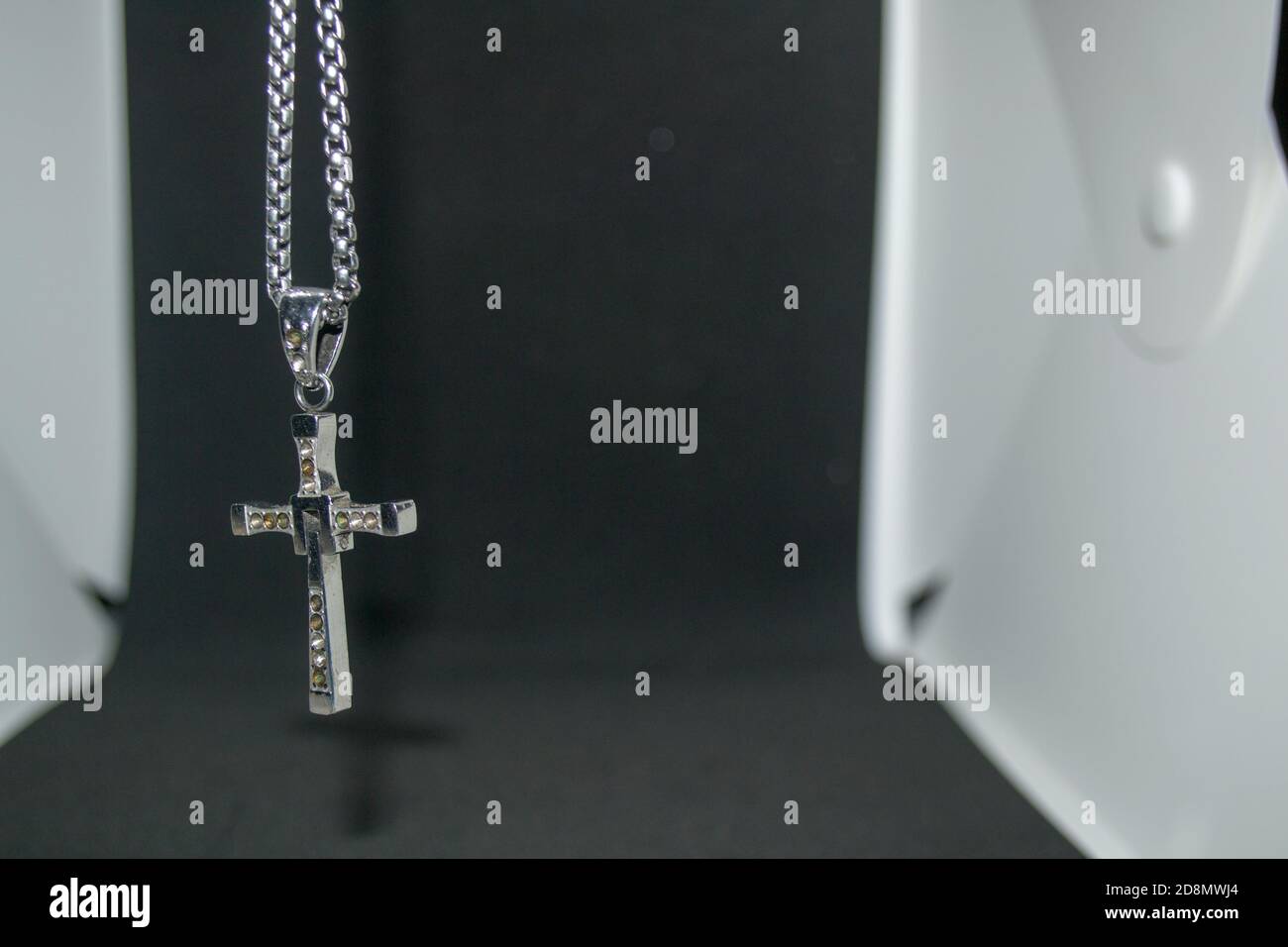 Nahaufnahme eines silbernen Metall christian Kreuz Halskette / Anhänger oder Silber Metall Kruzifix Halskette / Anhänger auf einem schwarz-weiß hängen Hintergrund Stockfoto