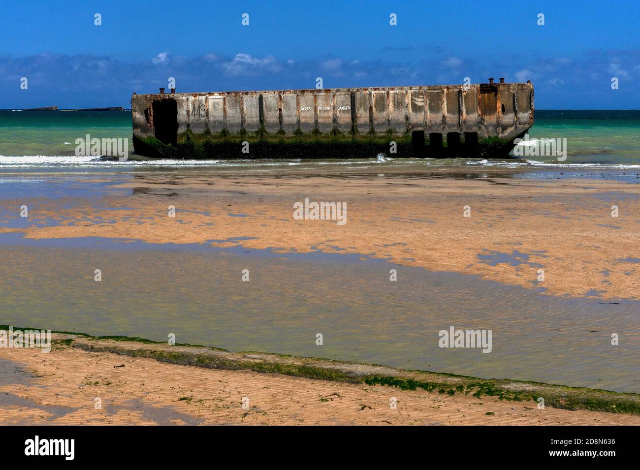 Bei Ebbe in Arromanches, Calvados, Normandie, Frankreich, Die Menschen können zu Fuß an den Rand des Wassers auf dem Zweiten Weltkrieg ‘Gold Beach’ zu erreichen - aber nicht betreten - vorgegossene Betonabschnitte von Port Winston oder Mulberry Harbour B. Dies war der 600,000-Tonnen-vorgefertigte tragbare Hafen, der über den Ärmelkanal geschleppt wurde, Vor der Küste montiert und dann für 10 Monate nach der Operation Overlord ‘D-Day’ Invasion vom 6. Juni 1944 verwendet, um 2.5 Millionen britische und kanadische Truppen, eine halbe Million Fahrzeuge und vier Millionen Tonnen Vorräte zu landen. Stockfoto