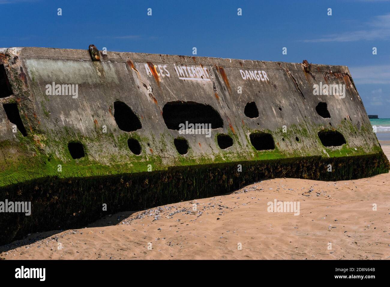 Eine gemalte Warnung verbietet den Zutritt zu diesem verfallenden Relikt des Zweiten Weltkriegs Juni 1944 ‘D-Day’ Landungen, die nur bei Ebbe am ‘Goldstrand’ in Arromanches-les-Bains, Calvados, Normandie, Frankreich zu Fuß erreicht werden. Die hier verbliebenen Lochbeton-Caissons waren Teil von Mulberry Harbour B, einem vorgefertigten Hafen, der aus England für die alliierte Invasion des nazibesetzten Frankreich geschleppt wurde. Wenn die Gezeiten steigen, füllen sich die Hohlbetonabschnitte wieder mit Meerwasser, mit der Gefahr, dass jemand darin eingeschlossen werden könnte. Der Hafen, vor der Küste montiert, wurde nach D-Day verwendet, um Millionen von Truppen, Fahrzeugen und Vorräten zu landen. Stockfoto