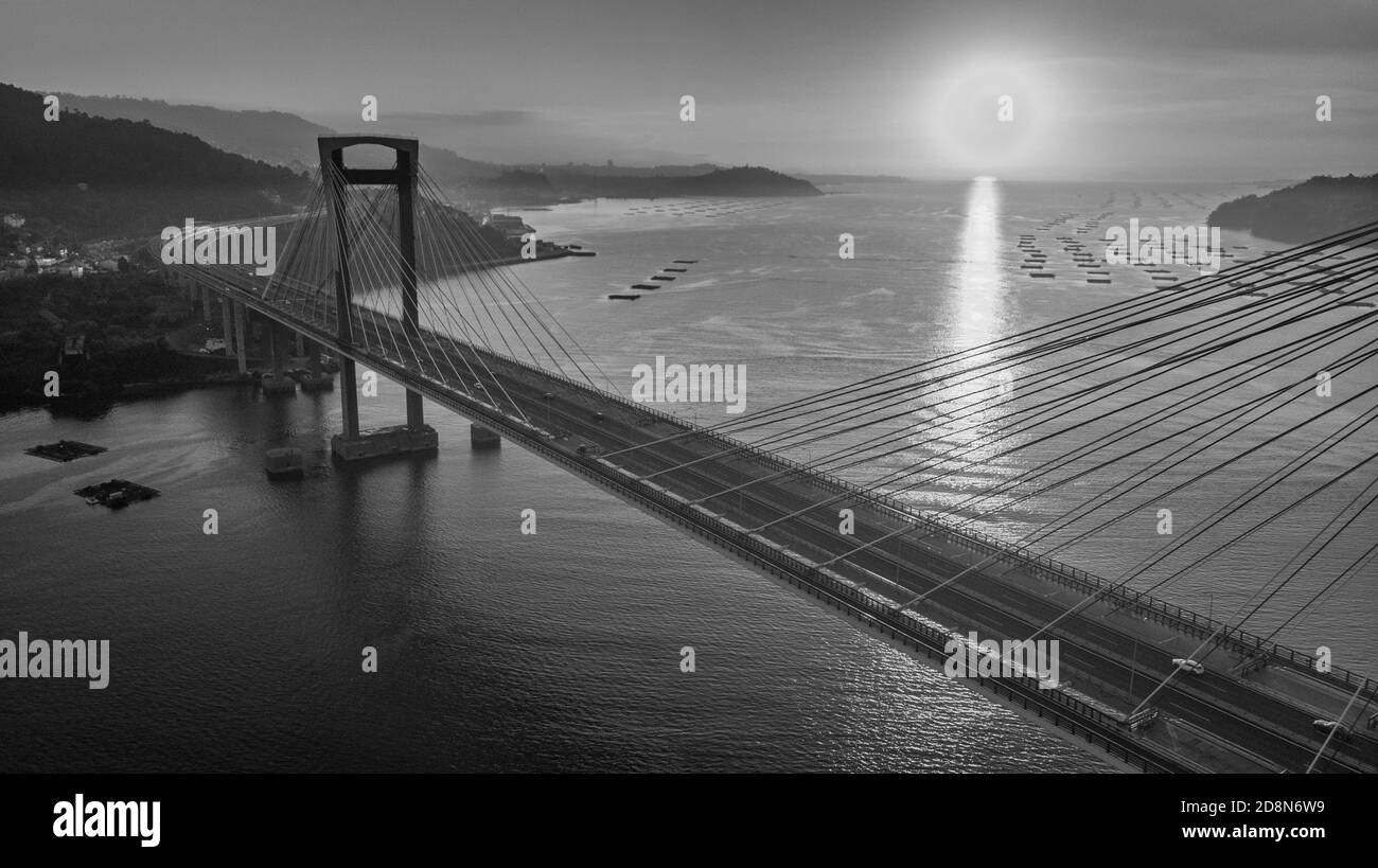 Luftaufnahme der Rande-Brücke bei Sonnenuntergang in schwarz-weiß. Puente de Rande, Rande, Vigo, Pontevedra, Galicien, Spanien Stockfoto