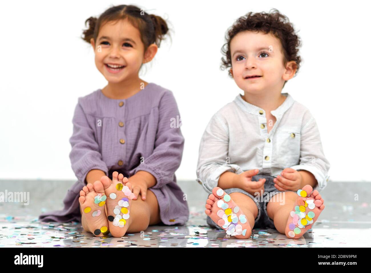 Kleine Kinder Füße mit bunten Konfetti bedeckt. Glückliche Kinder, die Spaß auf einer Party haben. Selektiver Fokus auf Sohle mit Konfetti. Stockfoto