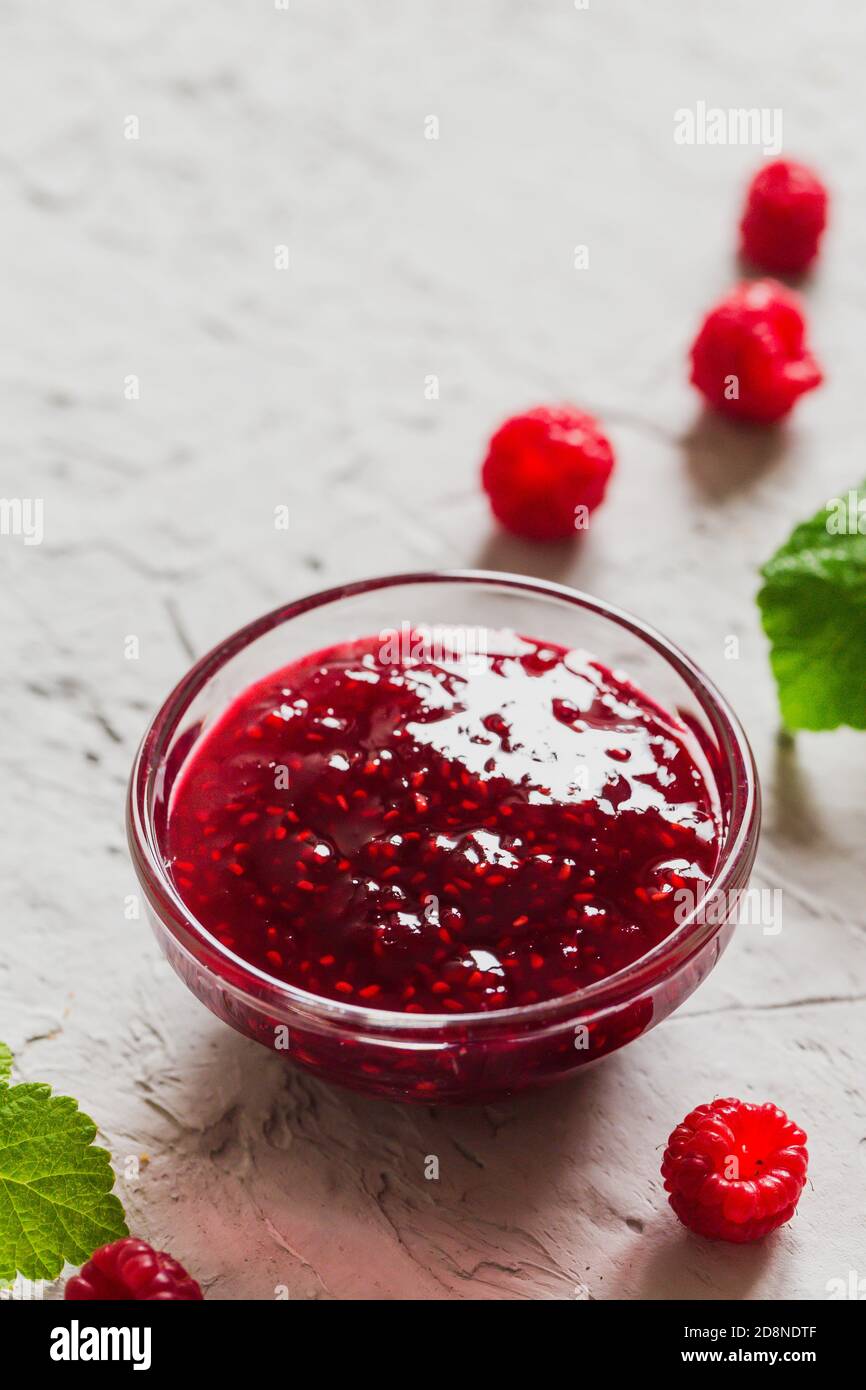 Hausgemachte Himbeermarmelade auf betontem Hintergrund mit frischen Himbeeren, selektiver Fokus. Stockfoto