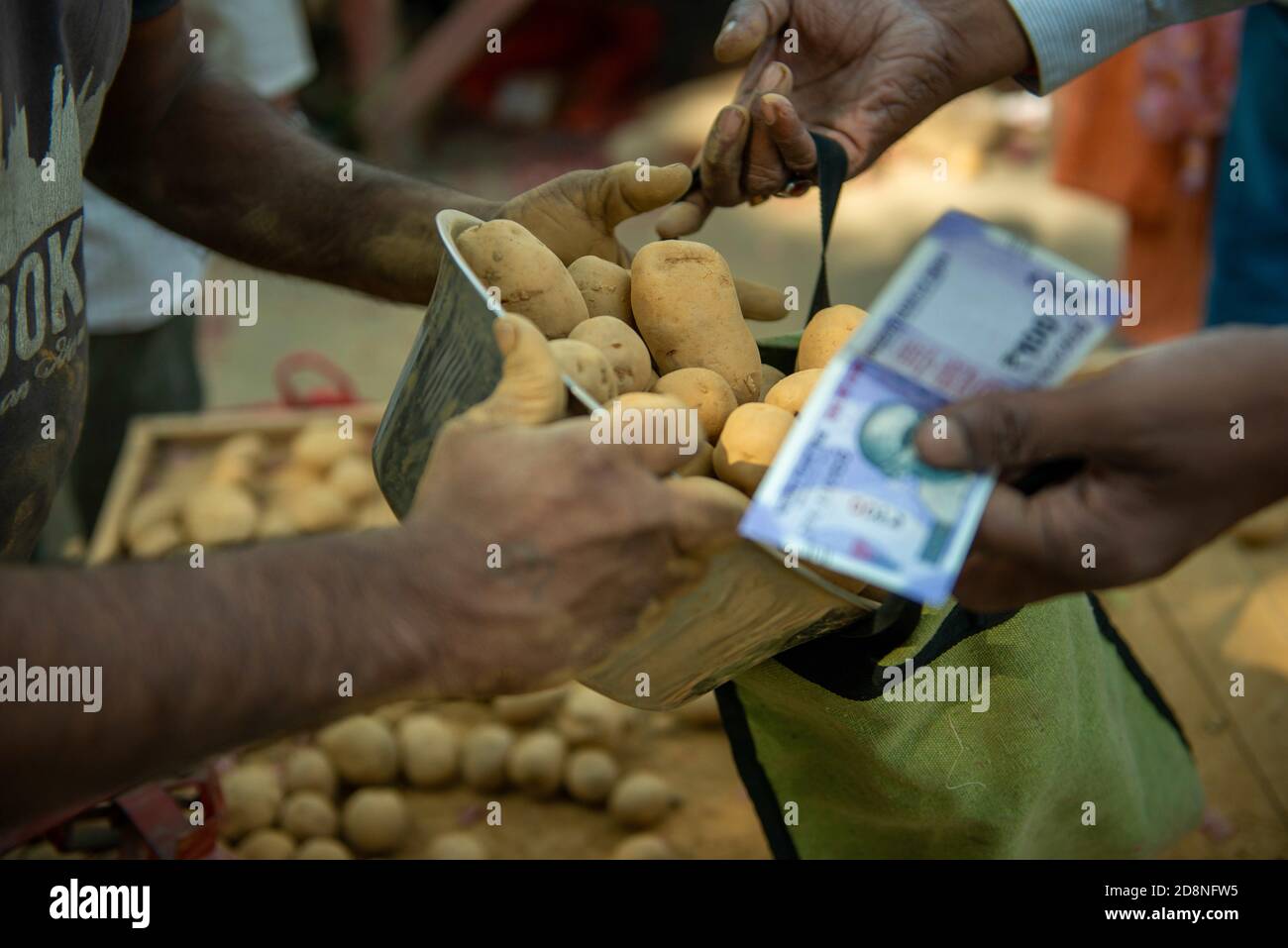 Ghaziabad, Indien. Oktober 2020. Ein Käufer, der Kartoffeln von einem Verkäufer mit Geld in den Händen am Sahibabad Gemüsemarkt bekommt.Inder kaufen Zwiebeln zu einem subventionierten Preis, der von der Landesregierung inmitten der steigenden Preise für Zwiebeln und Kartoffeln bereitgestellt wird. Kredit: Pradeep Gaur/SOPA Images/ZUMA Wire/Alamy Live Nachrichten Stockfoto