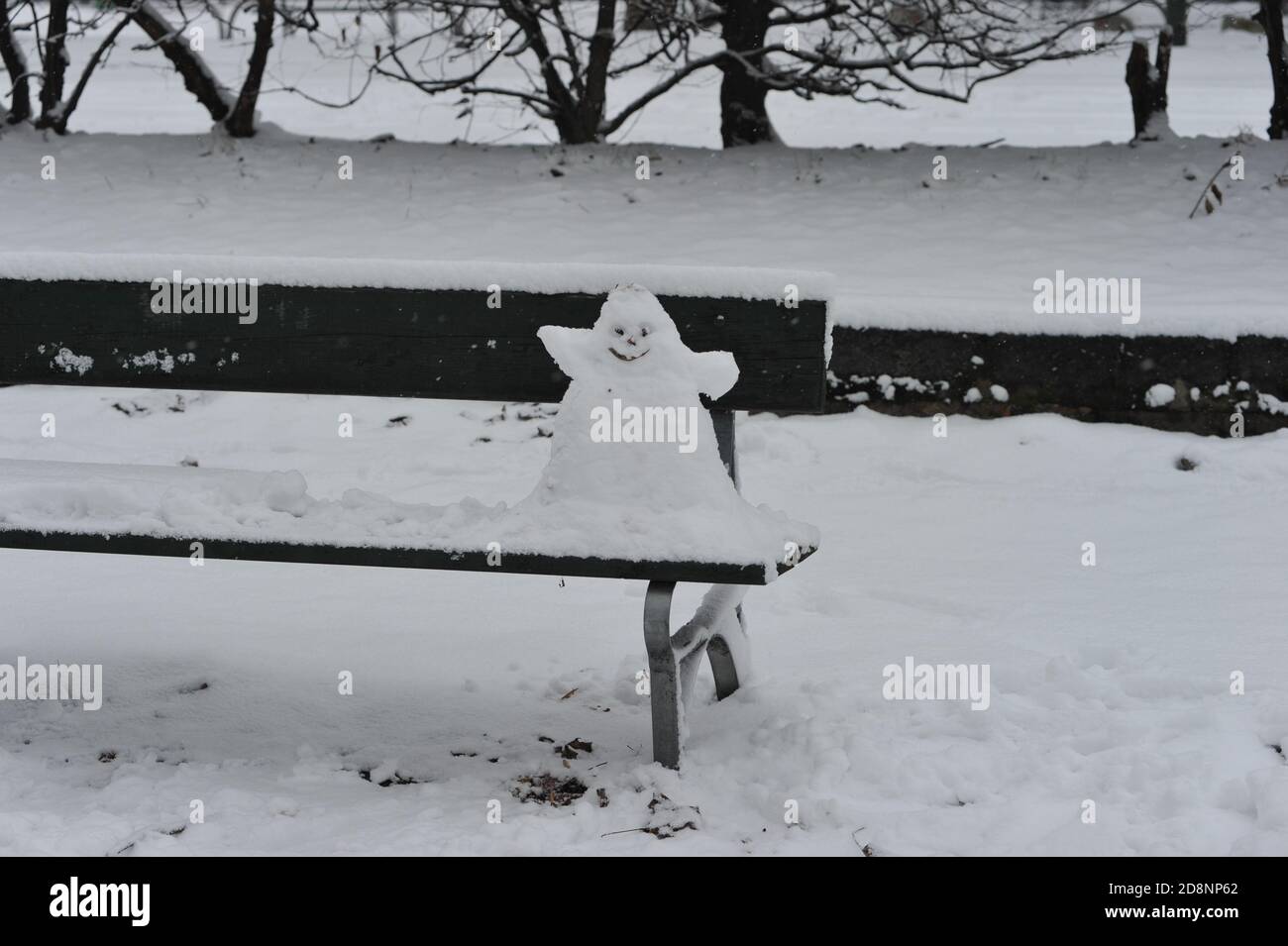 Kleiner und seltsamer Schneemann auf einer Bank Stockfoto