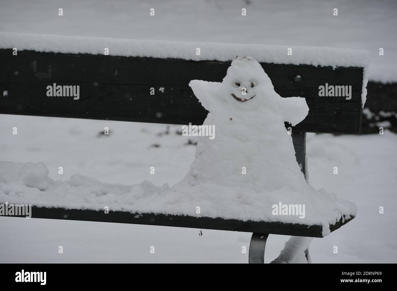 Kleiner und seltsamer Schneemann auf einer Bank Stockfoto