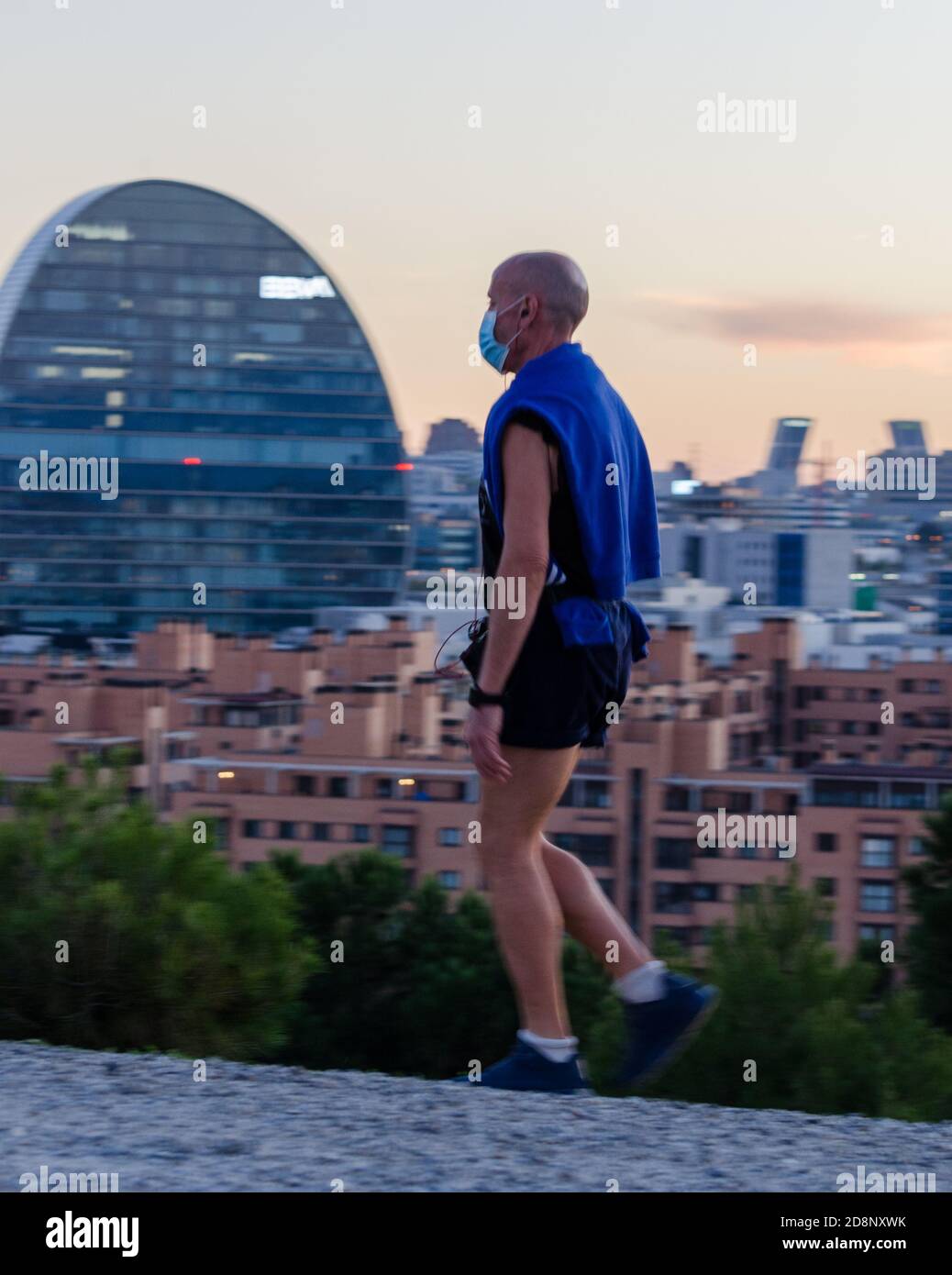 Läufer mit Gesichtsmaske mit Madrid Skyline im Hintergrund Stockfoto