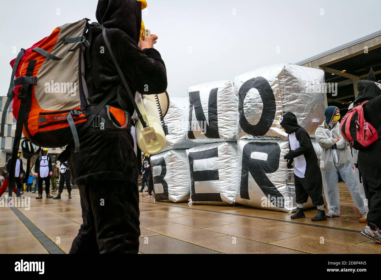 Protestor im Pinguin-Kostüm mit Megaphon am '#NOBER'-Schild als Klimaaktivist protestieren gegen die Eröffnung des Flughafens Berlin Brandenburg (ber). Stockfoto